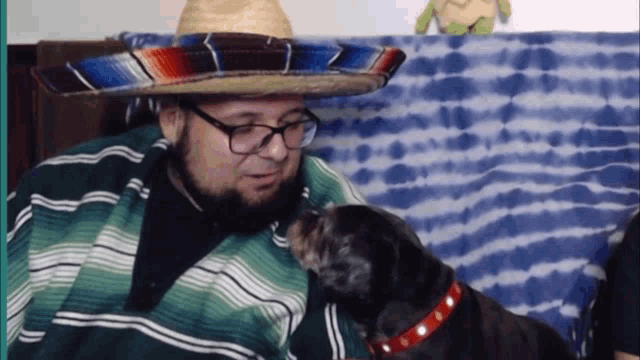 a man wearing a sombrero and glasses looks down at his dog
