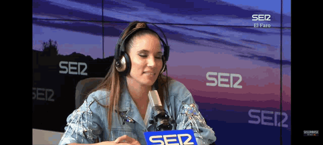 a woman wearing headphones is sitting in front of a microphone in front of a sign that says ser