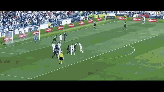 a group of soccer players are playing a game on a field with advertisements on the sidelines .