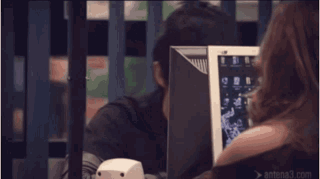 a man is smiling at a woman in front of a computer screen that says antena3.com on it
