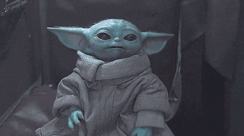 a baby yoda from star wars is sitting on a couch and making a funny face .