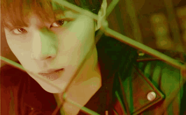 a close up of a young man 's face with a green light behind him