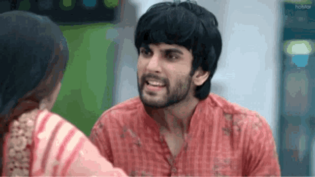 a man with a beard is talking to a woman in a pink dress .