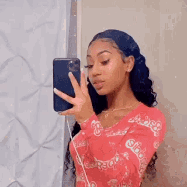 a woman is taking a selfie with her cell phone in front of a mirror .