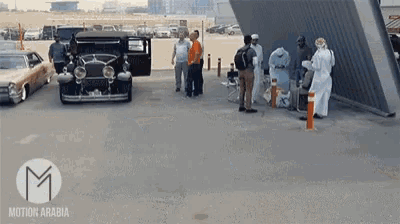 a group of people are gathered in a parking lot with a motion arabia logo in the corner