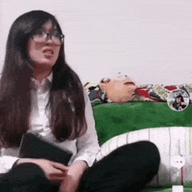 a woman wearing glasses is sitting on a couch with a stuffed animal .