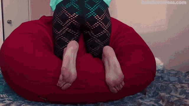 a woman 's feet are on a red bean bag chair with the website solesorceress.com visible in the corner