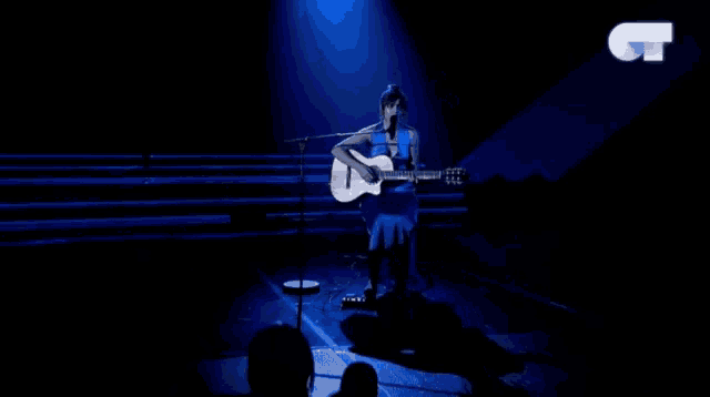 a woman playing a guitar and singing into a microphone