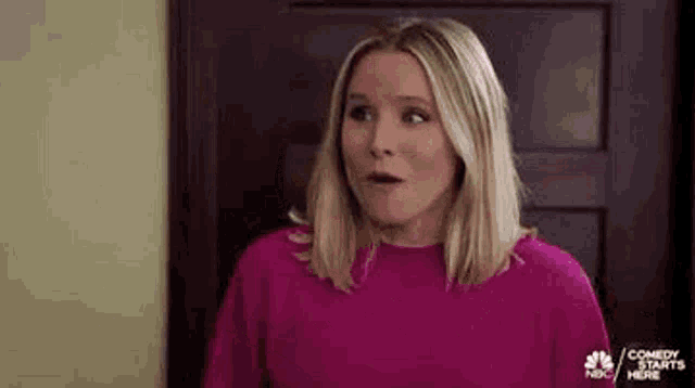 a woman in a pink sweater is making a surprised face .