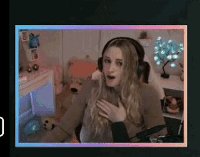 a woman wearing headphones is sitting in front of a microphone with her hand on her chest .