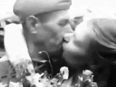 a black and white photo of a man and a woman kissing .