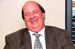 a bald man wearing a suit and tie is smiling with his eyes closed
