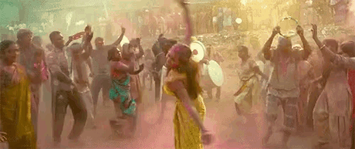 a woman is dancing in front of a crowd of people covered in powder .