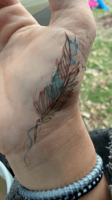 a person with a tattoo of a feather on their wrist