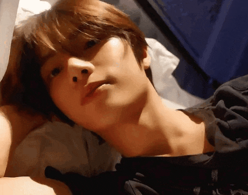 a close up of a young man laying on a bed with his head on a pillow .