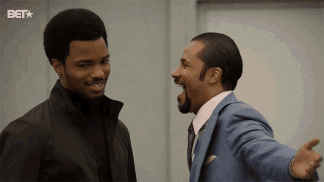 two men are standing next to each other with the bet logo in the background