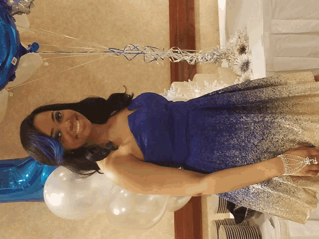a woman in a blue and gold dress is standing in front of balloons
