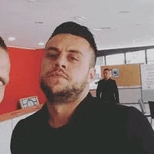 a man with a beard is making a funny face while standing next to another man .
