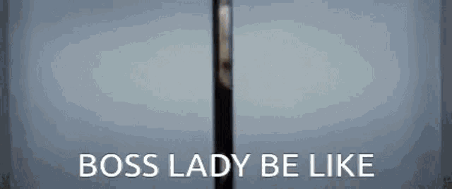 a woman is standing in front of a glass door with the words boss lady be like written on it .