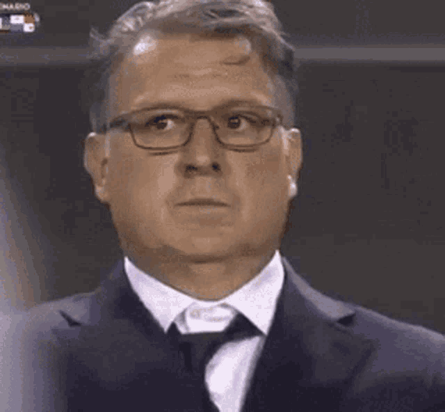 a man wearing glasses and a suit is making a funny face .