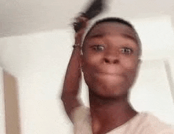 a young man is brushing his hair with a comb while making a funny face .