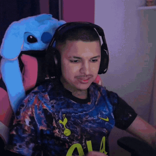 a man wearing headphones sits in a chair with a stuffed animal on his back