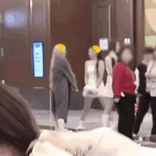 a blurry picture of a group of people including a woman in a red shirt and a woman in a white dress