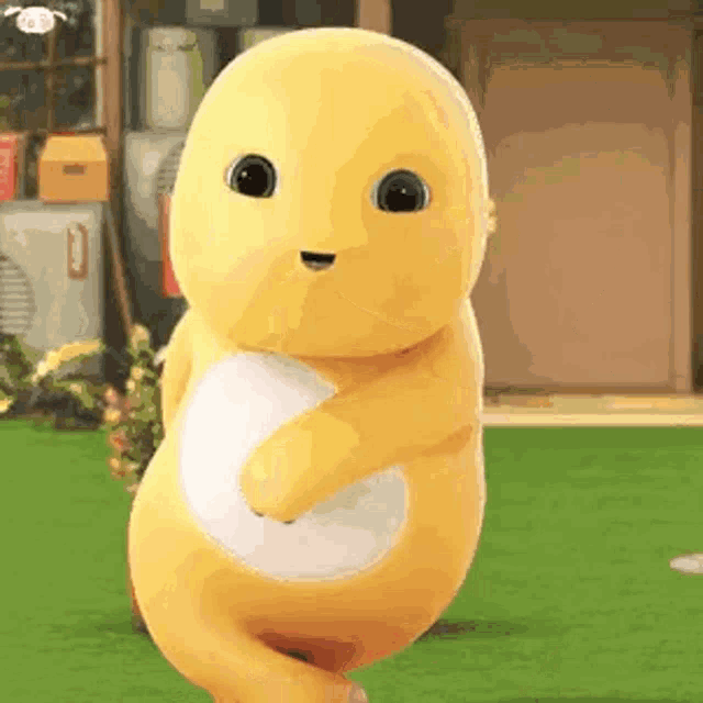 a yellow stuffed animal with a white belly is dancing on a lush green field .