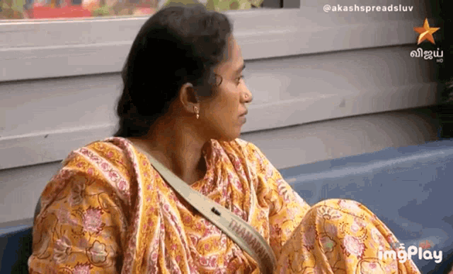 a woman is sitting on a couch with a messenger bag that says thamarai on it