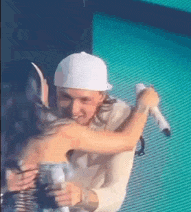 a man is holding a microphone and hugging a woman .