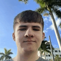 a young man is standing in front of a palm tree and taking a selfie .