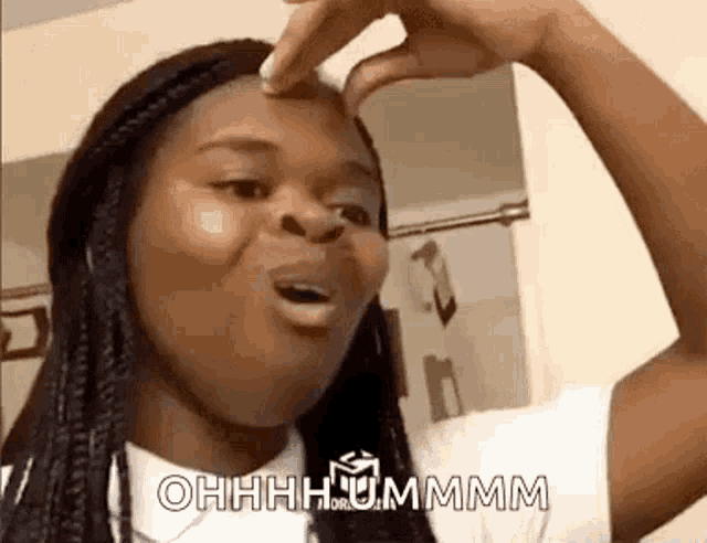 a woman is making a funny face while holding her hand to her forehead .