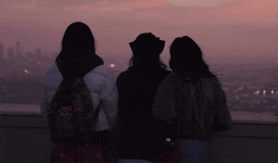 three women are standing on a balcony looking out over a city