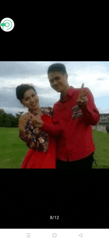 a man and a woman are standing next to each other in a field and giving a peace sign .