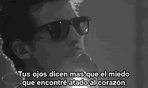 a black and white photo of a man singing into a microphone with the words tus ojos dicen mas que el miedo
