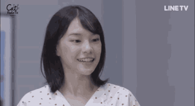 a young woman in a hospital gown is smiling and making a funny face .