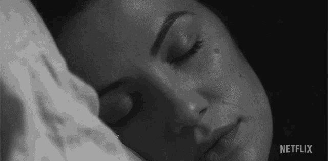 a black and white photo of a woman sleeping with her eyes closed and a netflix logo in the corner .