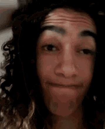 a young man with curly hair is making a funny face .