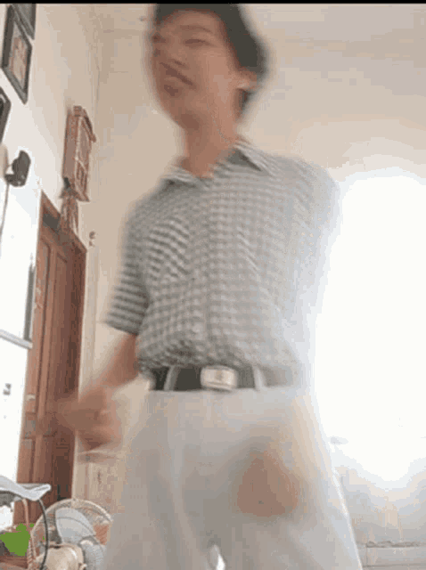 a man in a plaid shirt and white pants is standing in a room