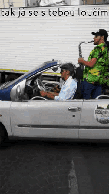 a man driving a car with carneval on the side of it