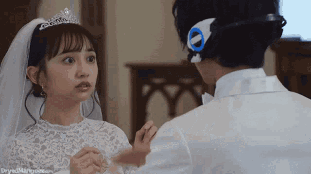 a woman in a wedding dress is looking at a man in a white tuxedo