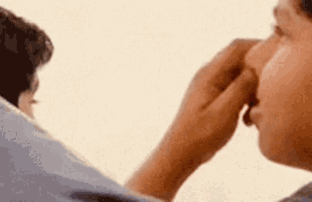 a man is touching another man 's nose .