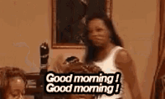 a woman is standing in a room with a sign that says `` good morning i good morning i '' .