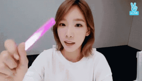 a woman in a white shirt is holding a pink light stick .