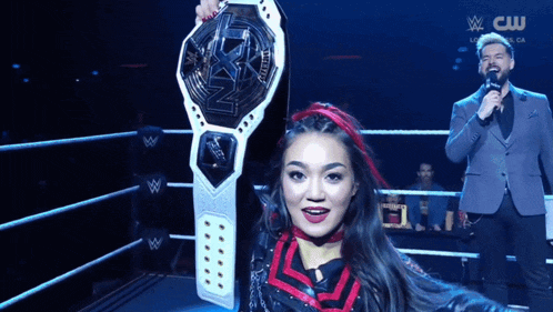 a woman in a wrestling ring is holding a wrestling championship