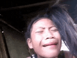 a young girl is making a funny face with her eyes closed .