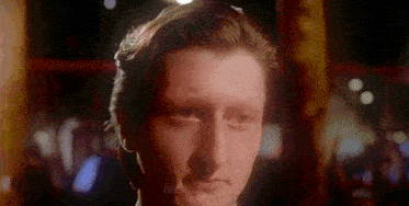 a close up of a man 's face in a dark room with a blurred background