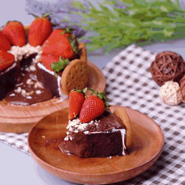 a slice of chocolate cake with strawberries and cookies on a wooden plate