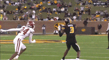 a football player with the number 3 on his jersey is trying to catch a pass from another player
