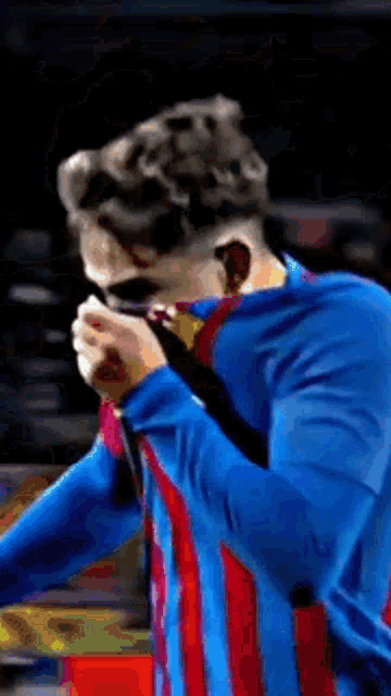 a man in a blue and red striped shirt is holding a microphone in his hand .
